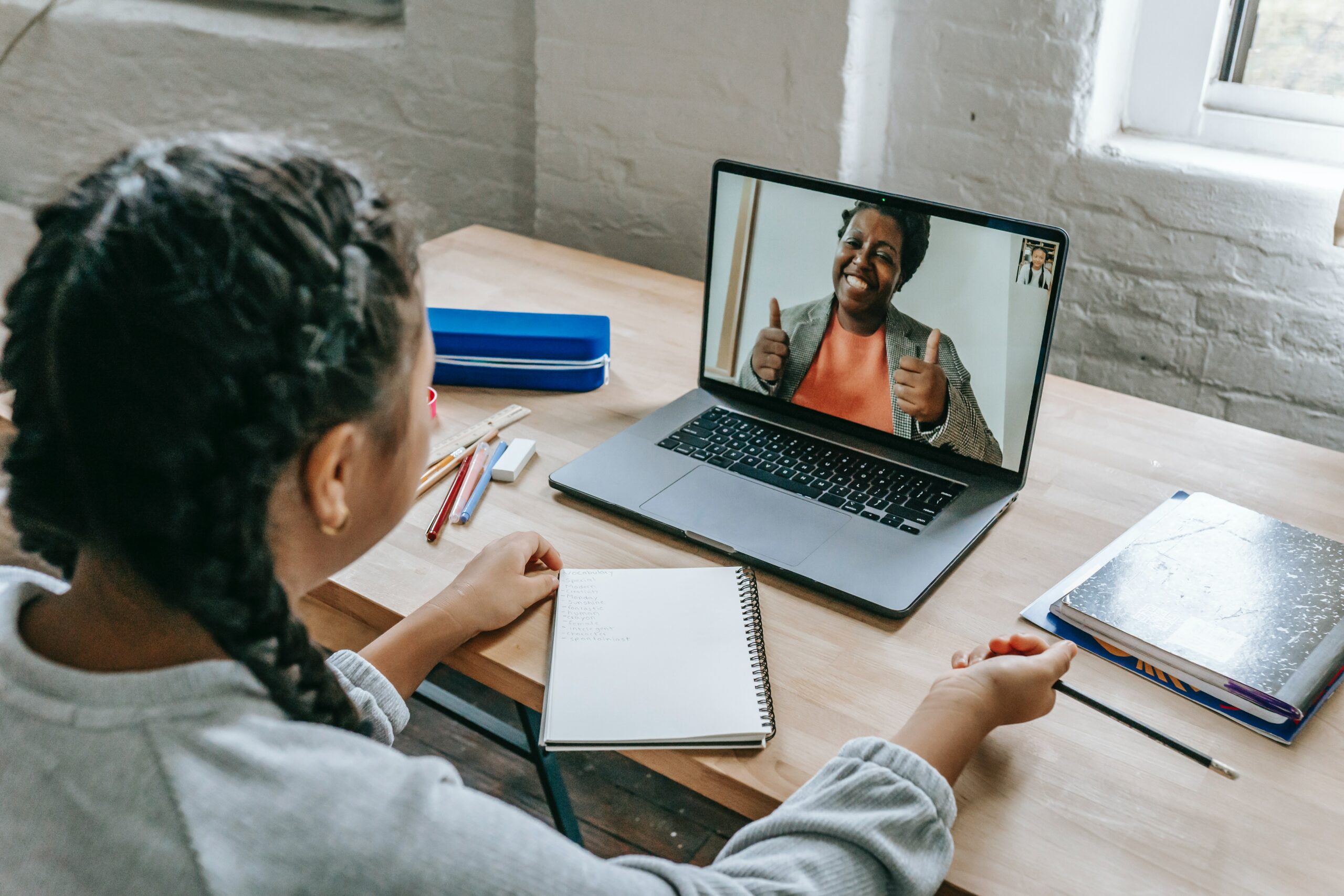 A laptop displaying a video call with a therapist, with the therapist and the patient both visible on the screen. Remote therapy monitoring for cognitive behavioral therapy (CBT) is depicted in the image.